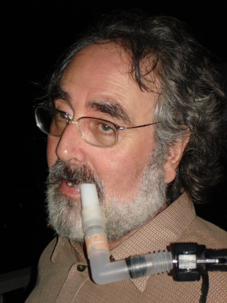close-up of Danny's face, graying hair and beard, glasses, ventilator hose
