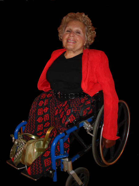 small woman with curly blonde hair sitting in her manual chair, head back, big smile