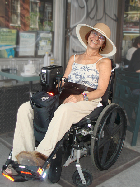 woman with big straw hat and big smile sitting in her wheelchair