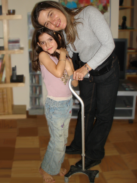 woman standing with cane, hugging her little girl