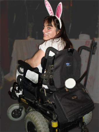 young woman sitting in her powerchair, wearing bunny ears and tail