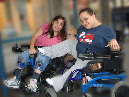 two girls, both in powerchairs, just clowning around